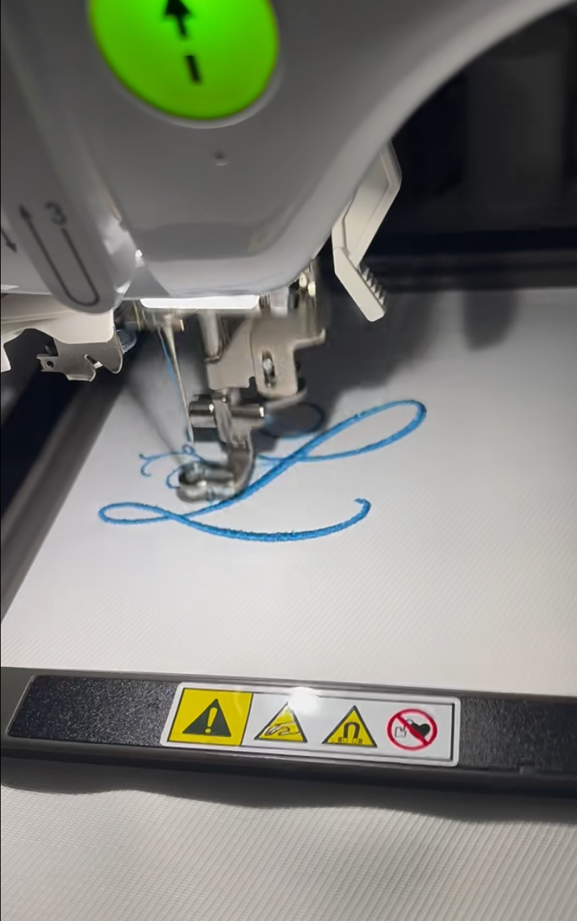 Embroidery machine stitching a blue name initial